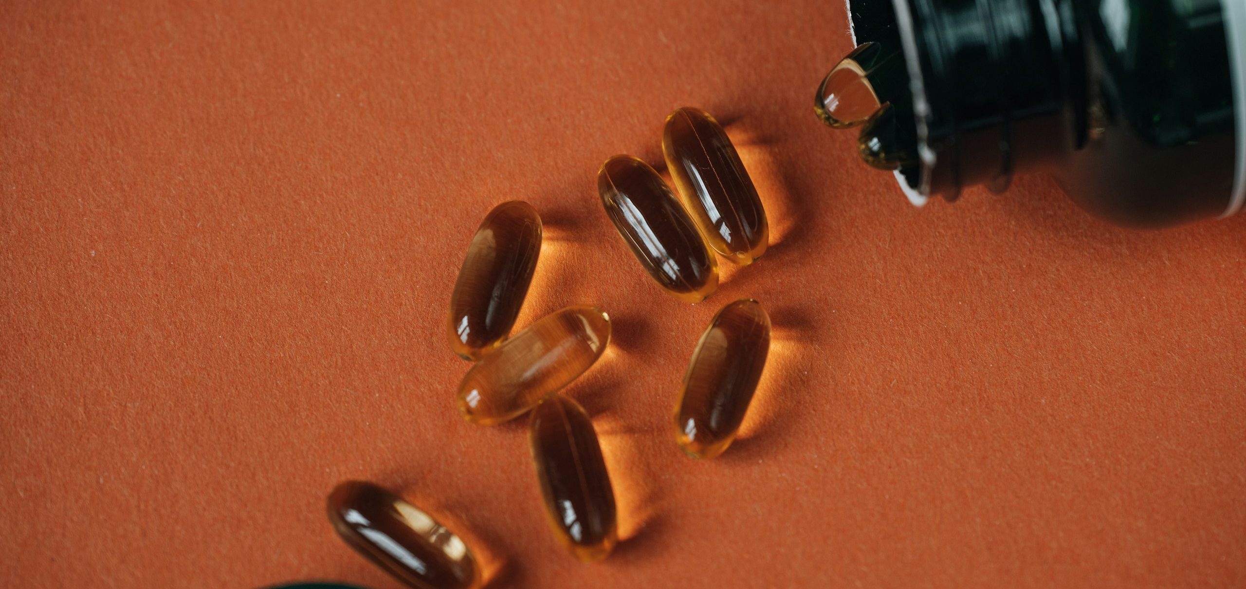 Golden softgel supplements beside a bottle