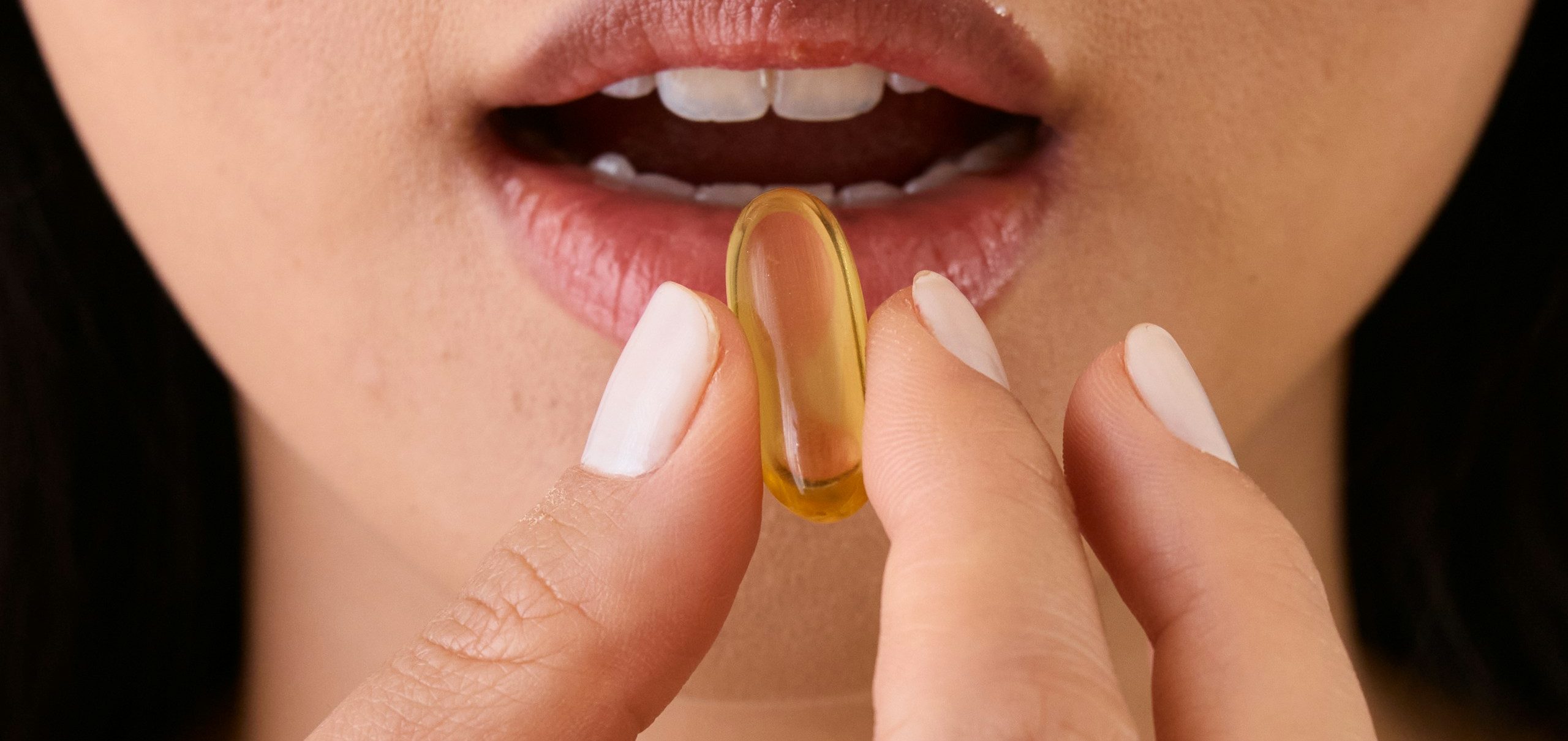 Woman holding a golden softgel supplement